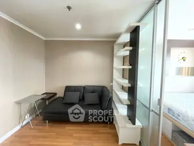 Modern living room with sleek black sofa and built-in shelving, adjacent to a cozy bedroom.
