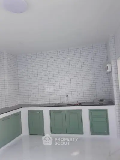 Modern kitchen with green cabinets and white subway tile backsplash