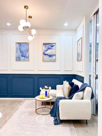 Elegant living room with modern decor, featuring stylish blue and white accents and chic lighting.