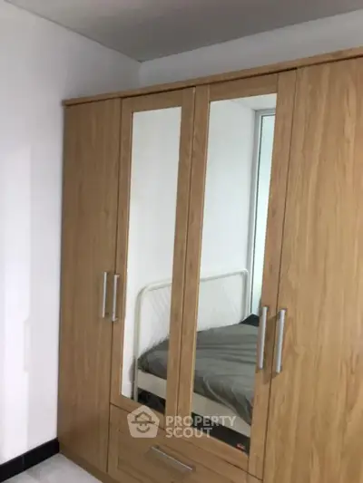 Spacious bedroom with wooden wardrobe and cozy bed setup
