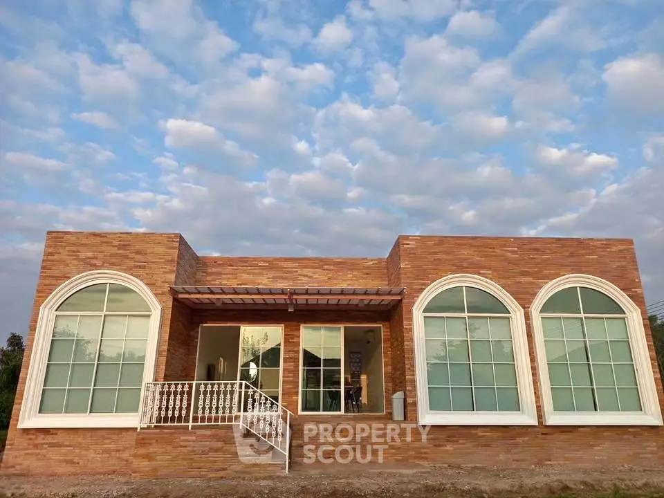 Charming single-story brick house with large arched windows and serene sky backdrop.