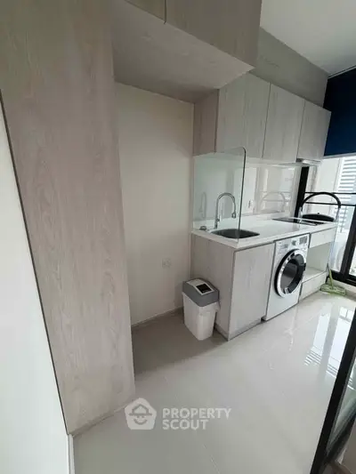 Modern kitchen with sleek cabinetry and built-in washing machine in a bright apartment.