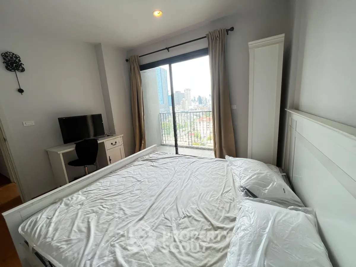 Spacious bedroom with city view and balcony access in modern apartment.
