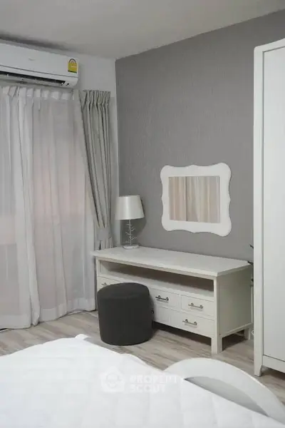 Chic bedroom with modern decor and air conditioning, featuring a stylish vanity and elegant curtains.
