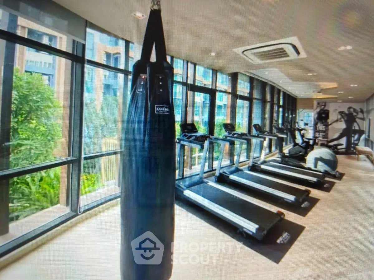 Modern gym with treadmills and punching bag in luxury apartment building