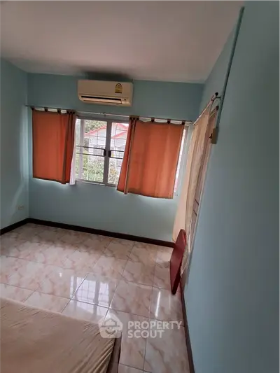 Spacious bedroom with air conditioning and large windows in a cozy home.