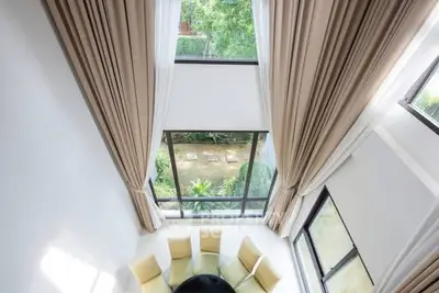 Stunning high-ceiling living room with large windows and garden view.