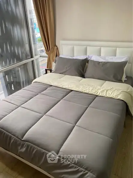 Cozy bedroom with modern decor and large window offering city views, perfect for relaxation.