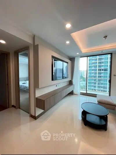 Modern living room with sleek design and city view, featuring a wall-mounted TV and stylish furniture.
