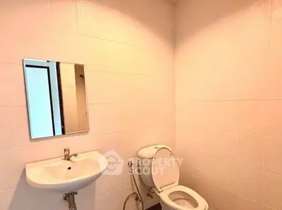 Modern bathroom with sleek white tiles and compact fixtures.