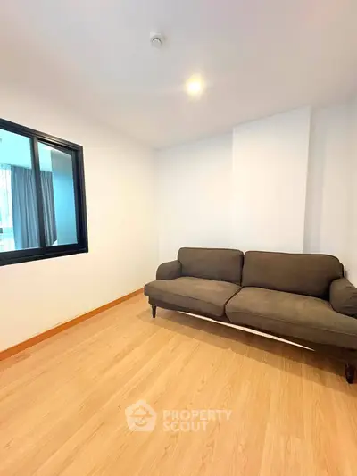 Spacious living room with modern sofa and wooden flooring, perfect for relaxation and entertaining guests.