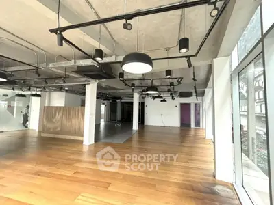 Spacious modern interior with wooden floors and industrial lighting, ideal for office or studio setup.