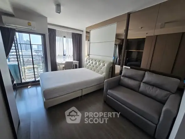 Modern bedroom with city view, featuring a cozy bed and stylish sofa.