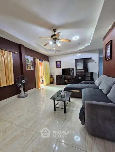 Spacious living room with modern decor, ceiling fan, and natural light, perfect for relaxation and entertainment.