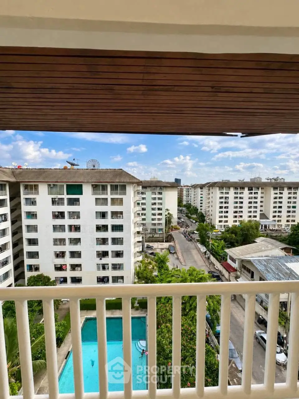 Stunning balcony view of modern apartment complex with pool and cityscape.