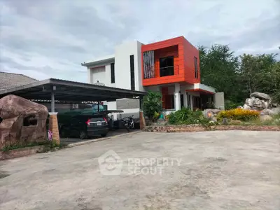 Modern two-story house with unique orange facade and spacious driveway