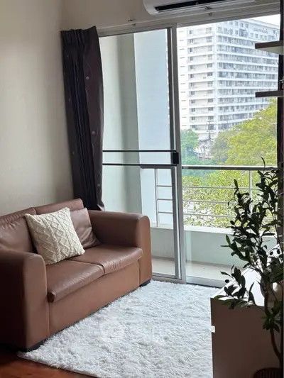 Cozy living room with brown leather sofa and balcony view in modern apartment.