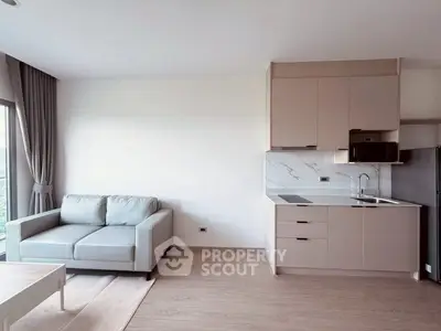 Modern living room with sleek kitchen in open layout, featuring stylish sofa and natural light.