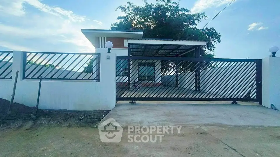 Modern single-story house with gated entrance and spacious driveway.