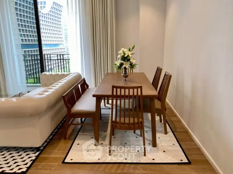 Elegant dining area with wooden table and chairs, adjacent to a cozy living space with a modern sofa.