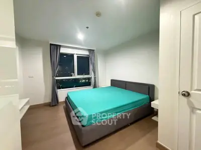 Spacious bedroom with city view and modern furnishings in a high-rise apartment.