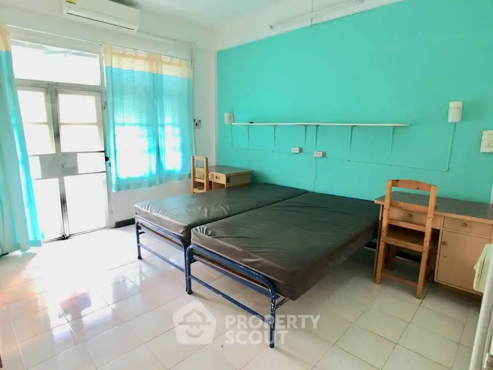 Spacious bedroom with twin beds and natural light in a vibrant teal-themed decor.
