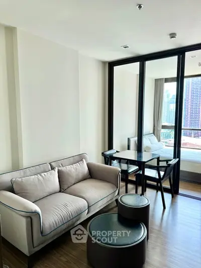 Modern living room with cozy sofa and dining area, featuring floor-to-ceiling windows and city view.