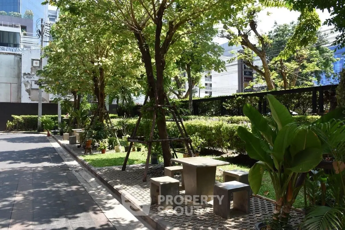 Charming urban garden with seating area, lush greenery, and modern city backdrop.