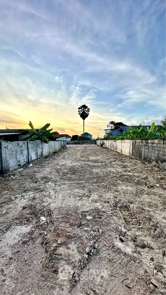 Expansive land plot with potential for development, featuring a serene sunset backdrop and lush greenery.