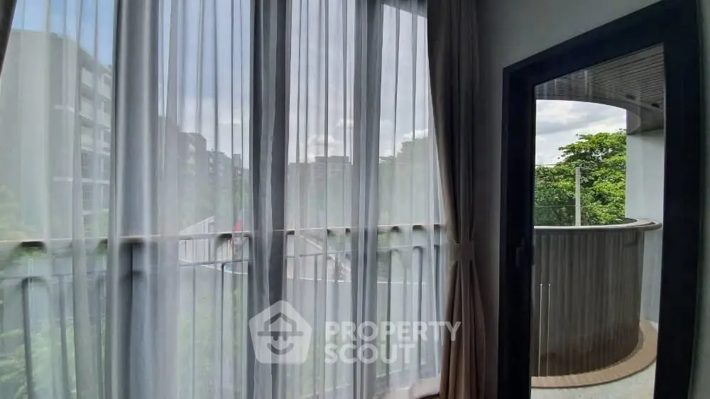 Spacious balcony with city view and sheer curtains in modern apartment