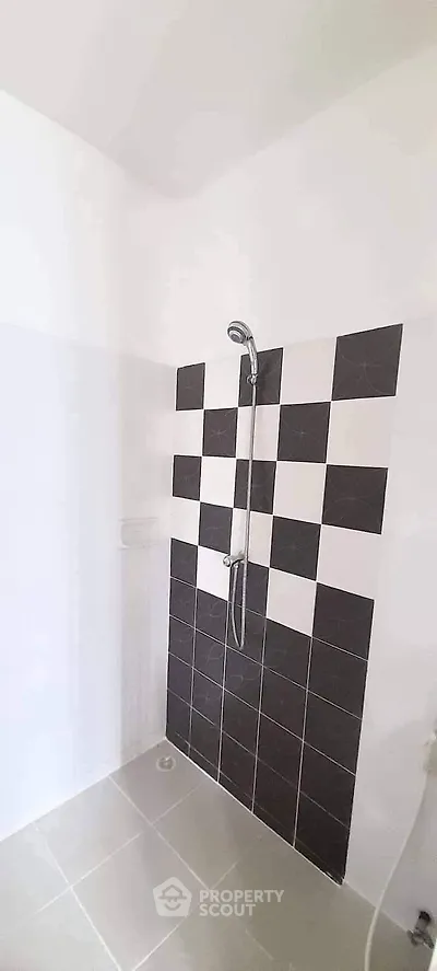 Modern bathroom with stylish black and white checkered tiles and sleek shower design.