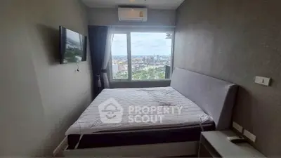 Modern bedroom with city view, featuring a sleek bed and wall-mounted TV, perfect for urban living.