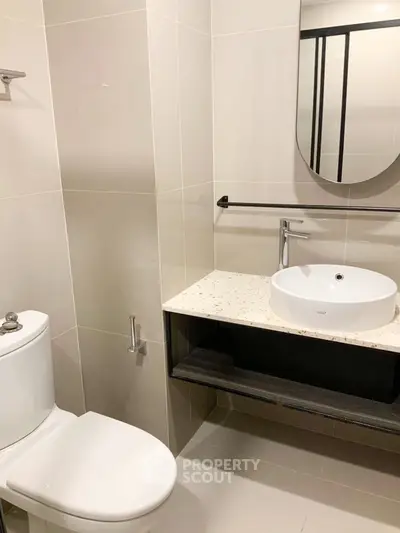 Modern bathroom with sleek fixtures and elegant design, featuring a round basin and wall-mounted mirror.