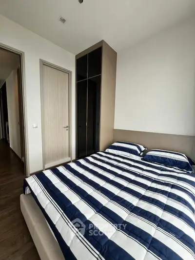 Modern bedroom with stylish striped bedding and sleek wardrobe in a contemporary apartment.