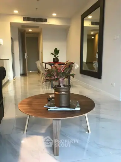 Modern living room with stylish coffee table and large mirror, showcasing elegant interior design.