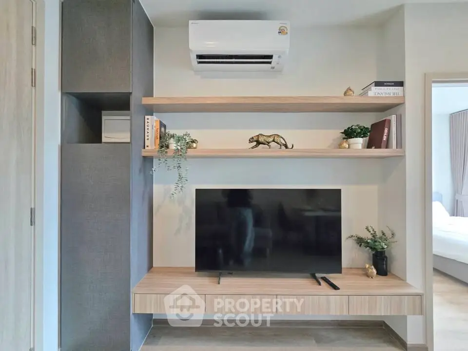 Modern living room with sleek TV unit and air conditioning, featuring stylish shelves and decor.