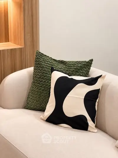 Stylish modern living room with cozy beige sofa and decorative pillows, perfect for relaxation.