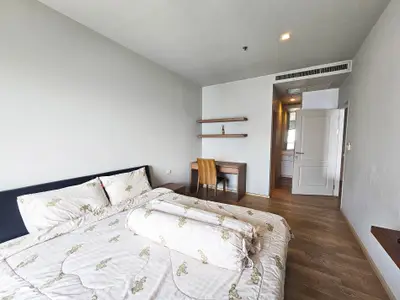 Spacious bedroom with modern decor and natural light, featuring a cozy bed and study area.