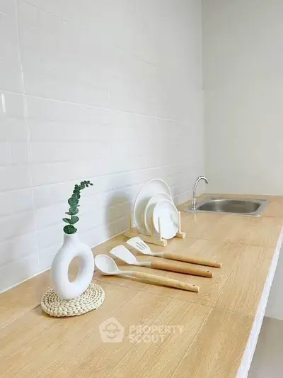 Modern minimalist kitchen with wooden countertop and sleek white backsplash.