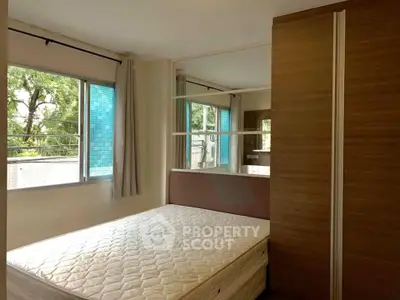 Spacious bedroom with large windows and ample natural light, featuring a comfortable bed and modern wardrobe.