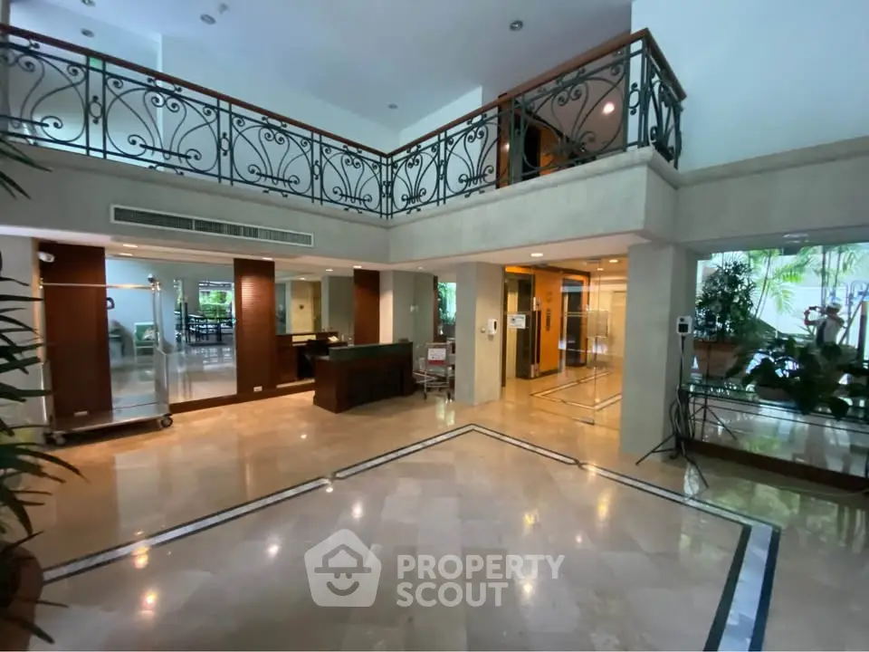 Elegant building entrance with marble floors and stylish railing, showcasing luxury and sophistication.