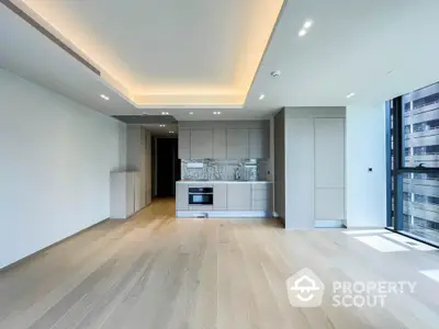 Modern open-layout kitchen with sleek cabinetry and hardwood floors in a bright apartment.