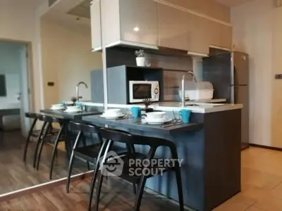 Modern kitchen with sleek design and dining area, featuring a microwave and refrigerator.