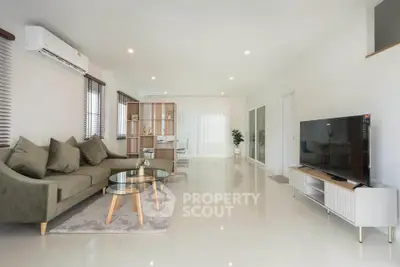 Spacious modern living room with sleek furniture and large TV, perfect for relaxation.