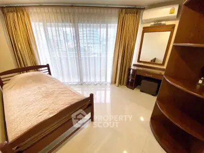 Spacious bedroom with elegant wooden furniture and large window offering natural light.