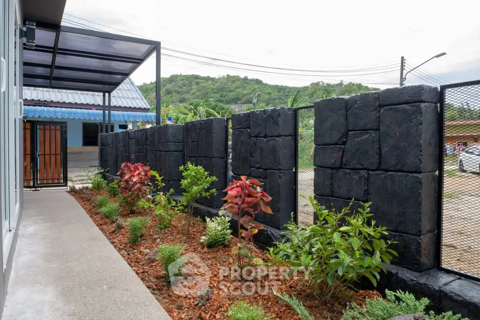 Charming garden view with modern stone fence and lush greenery, perfect for outdoor relaxation.