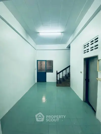 Spacious interior with tiled floor and staircase, ideal for customization.