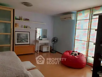 Cozy bedroom with modern decor and natural light, featuring a bean bag and air conditioning.