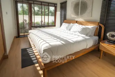 Luxurious bedroom with elegant wooden furniture and large windows offering serene garden views.