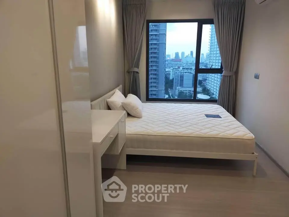Modern bedroom with city view, featuring a comfortable bed and sleek furnishings in a high-rise apartment.